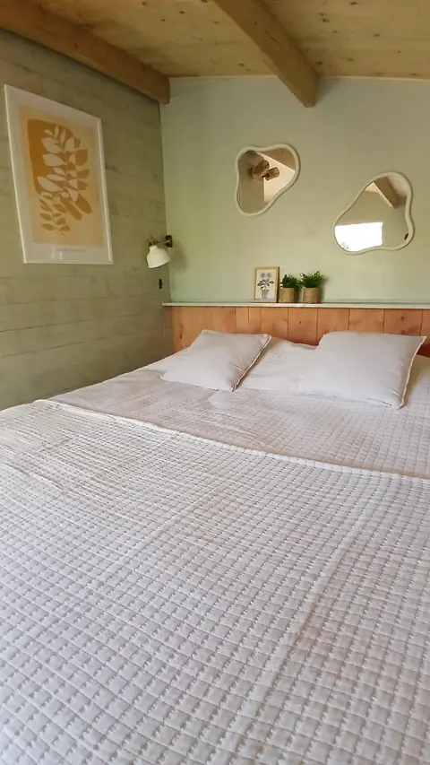 Tweepersoonsbed met spiegeltjes aan de muur in De Appel