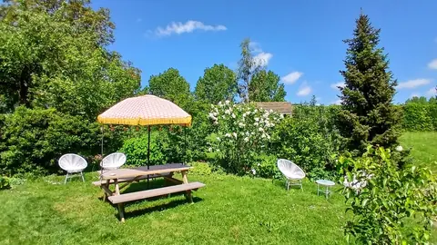 Picknicktafel met parasol en witte stoeltjes in de zonnige tuin